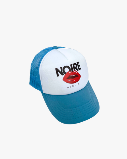 Front view of Noire Berlin/Noire Clothing Baby Blue Trucker Cap featuring red lips logo and white front panel.