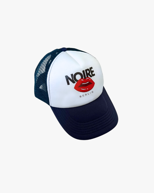Front view of Noire Berlin/Noire Clothing Midnight Blue Trucker Cap featuring red lips logo and white front panel.